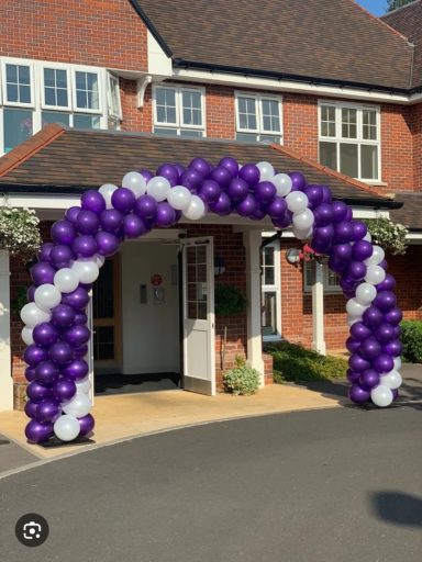 Spiral Balloon Arch Archway made of purple and white balloons at an entrance.