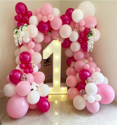 Balloon Garland A large illuminated number one surrounded by pink, white, and purple balloons.