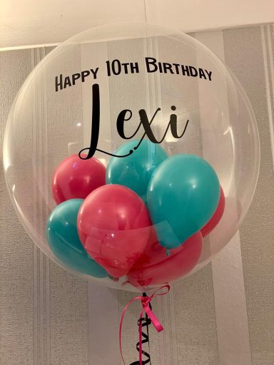 Filled Helium Bobo Balloon Transparent balloon with "Happy 10th Birthday Lexi" and colourful balloons inside.